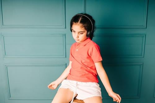 Süßes Mädchen hört Musik mit Kopfhörern bezaubernd allein attraktiv Hintergrund schön blau sorgenfrei lässig heiter Kind Kindheit Farbe niedlich Tanzen genießen