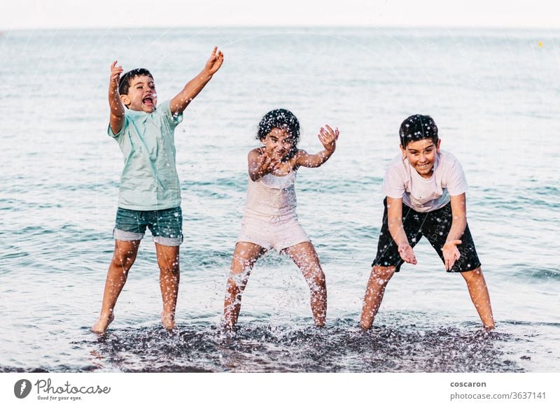 Drei Kinder spielen am Strand mit dem Wasser Aktion aktiv schön blau Junge hell heiter Konzept Tropfen genießen frisch Spaß lustig Mädchen Fröhlichkeit Glück