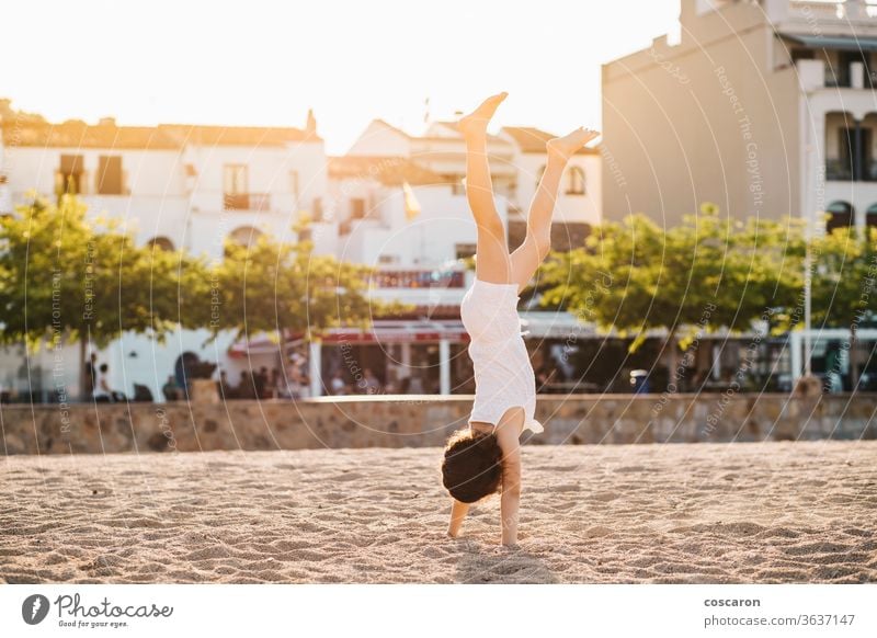Kleines Mädchen macht einen Handstand am Strand akrobatisch aktiv Hintergrundbeleuchtung Gleichgewicht schön Kind Küste niedlich Tanzen genießen Übung Fitness
