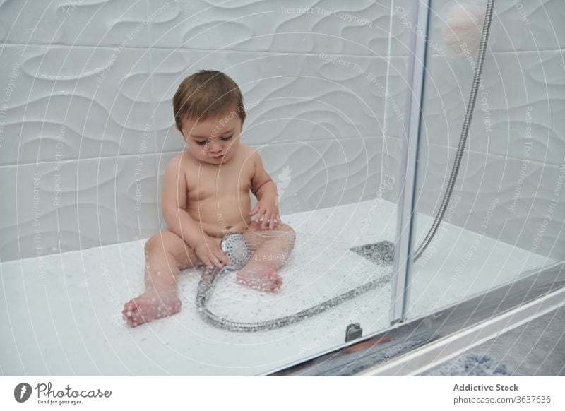 Kleines Baby unter der Dusche Wasser genießen Hygiene Bad niedlich Kleinkind wenig Verfahren Kind bezaubernd Kindheit Freude Pflege Lächeln sitzen Routine