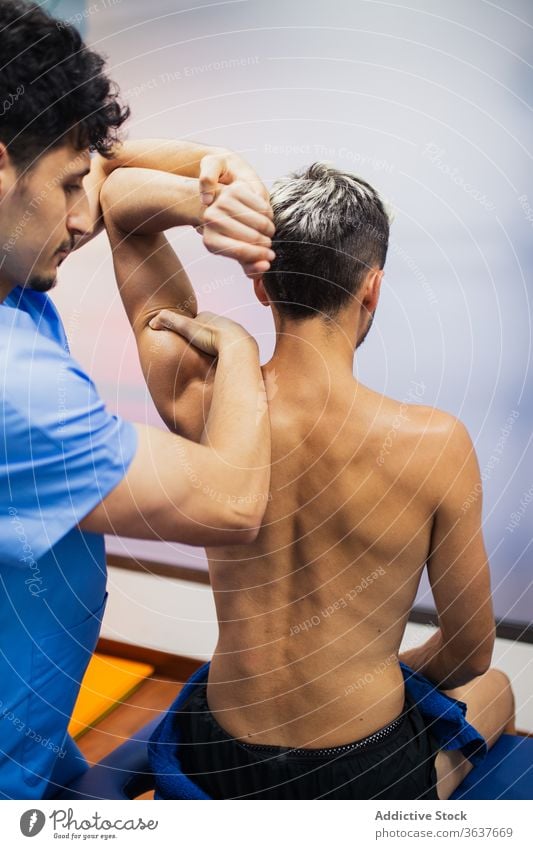 Chiropraktiker untersucht den Arm eines sportlichen männlichen Patienten in der Klinik untersuchen geduldig Gesundheitswesen Rehabilitation Sanitäter Kontrolle