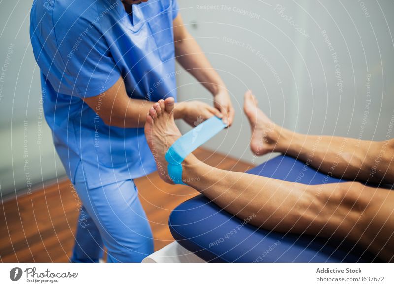 Anonymer Osteopath legt elastisches Klebeband auf den Fuß des Patienten Chiropraktiker geduldig kinesio Wiederherstellung Gesundheitswesen Unterstützung Uniform
