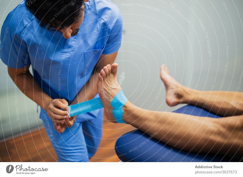 Anonymer Osteopath legt elastisches Klebeband auf den Fuß des Patienten Chiropraktiker geduldig kinesio Wiederherstellung Gesundheitswesen Unterstützung Uniform