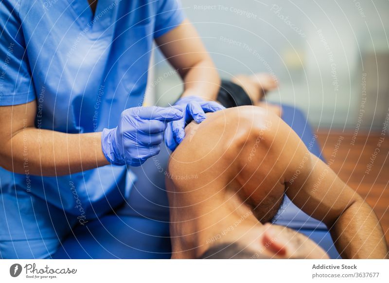 Unbekannter Arzt schießt einem anonymen Sportler eine Nadel in den Rücken einstecken geduldig Bein Akupunktur Behandlung Verfahren steril Handschuh