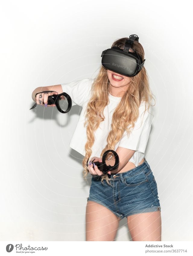Zufriedene Frau spielt Spiel in VR-Headset Virtuelle Realität spielen Videospiel Regler Schutzbrille Atelier unterhalten aufgeregt Erfahrung simulieren