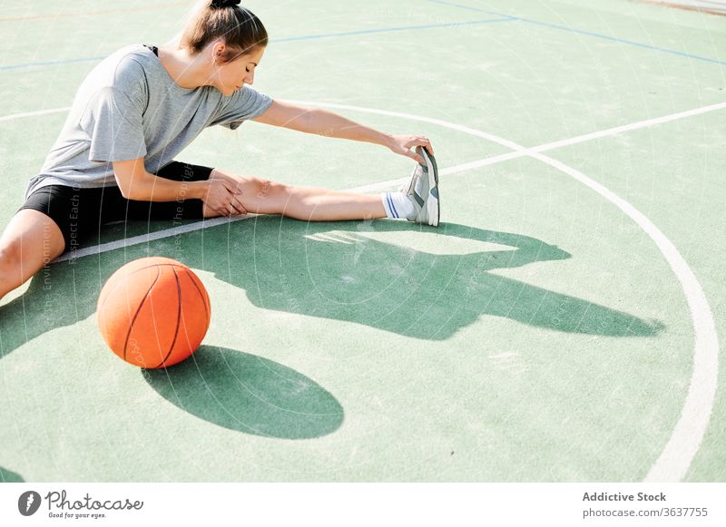 Basketballspielerin beim Stretching auf dem Sportplatz Frau Dehnung Übung Aufwärmen Sportpark Training vorbereiten Spieler Ball Gericht Aktivität Lifestyle