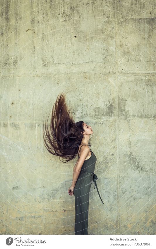 Junge Frau mit fliegenden Haaren fliegendes Haar Anmut Schönheit lange Haare Großstadt charmant Angebot urban Harmonie schlank Steinwand schäbig verwittert