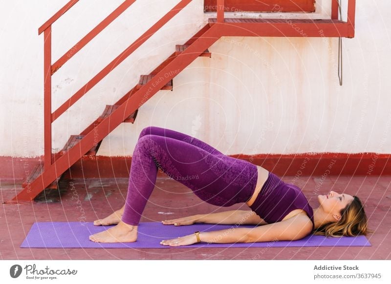 Ruhige, Yoga praktizierende Frau in Brücken-Asana Brückenstellung Gleichgewicht Sportkleidung Lügen Windstille Harmonie setu bandha sarvangasana ruhig