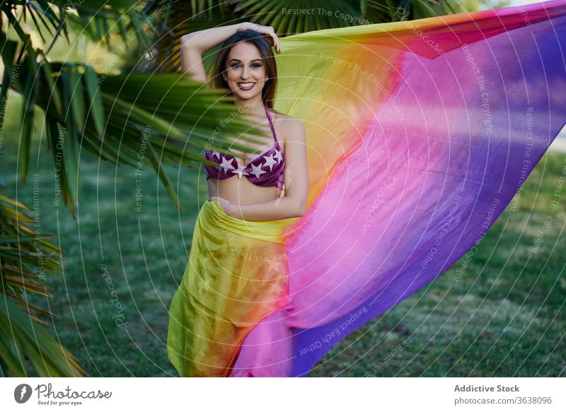 Lächelnde ethische Frau führt orientalischen Tanz auf Tänzer Bauch Tanzen Orientalisch ausführen Park Sonnenuntergang Anmut Tuch ethnisch Tradition Tracht grün