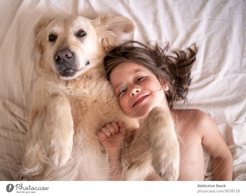 Glückliches Mädchen liegt mit Hund auf zerknittertem Bettlaken ruhen Zuneigung Begleiter Zusammensein idyllisch heimwärts Harmonie Schot hovawart Haustier