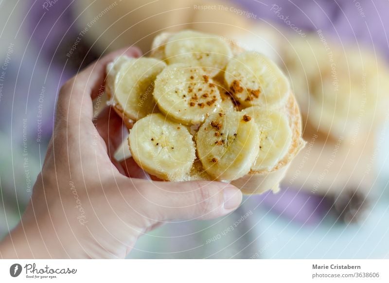 Flache Tiefenschärfe der Hand, die ein mit Bananenscheiben und Zimtpulver belegtes Toastbrot hält Veganer natürlich heimwärts selbstgemacht lecker Vegetarier