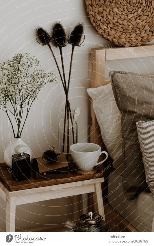 Schlafzimmerdetail mit Holzhocker, Keramikbecher und Trockenblumen Hocker Bett Blume weiß natürlich träumen Idee Morgen Gefühl Vase skandinavisch Stil