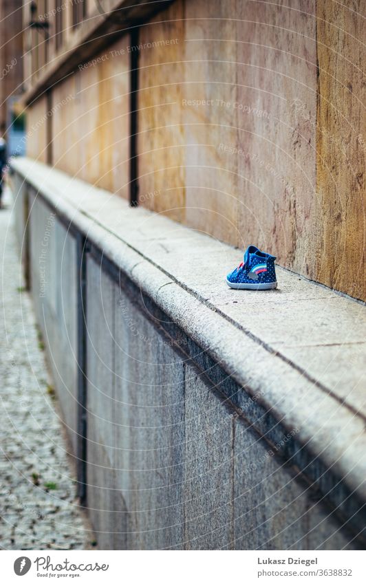 Kleiner Kinderschuh an der Wand Schuh klein Schuhe Kinderschuhe Schuhsohle Farbfoto Bekleidung Turnschuh allein Außenaufnahme Tag verlorener Schuh