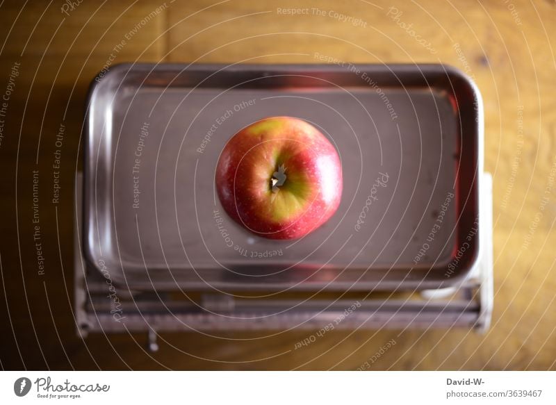ein Apfel wird gewogen Waage wiegen Obst messen ermitteln Gewicht Handel Ladengeschäft nostalgisch