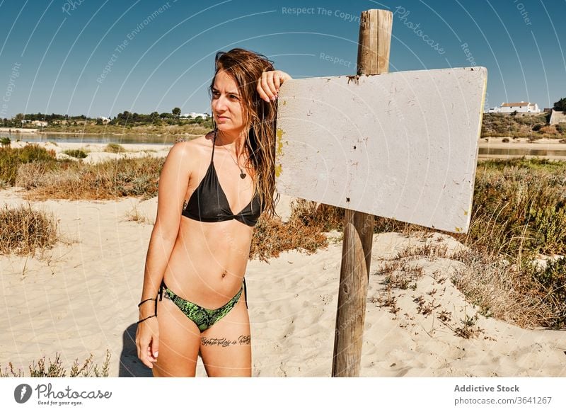 Fröhliche Reisende im Badeanzug am Strand MEER Zeichen Frau Bikini Tourismus Strandpromenade Urlaub Sommer Sand schlank reisen Feiertag Badebekleidung Küste