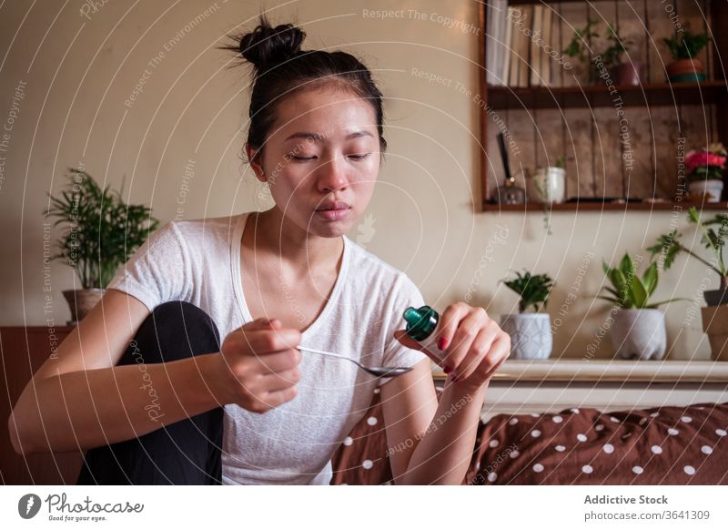Ethnische Frau behandelt Kälte mit Mischung Husten Sirup krank Leckerbissen Medizin Erkältung haben ertragen Grippe asiatisch ethnisch unwohl müde heimwärts