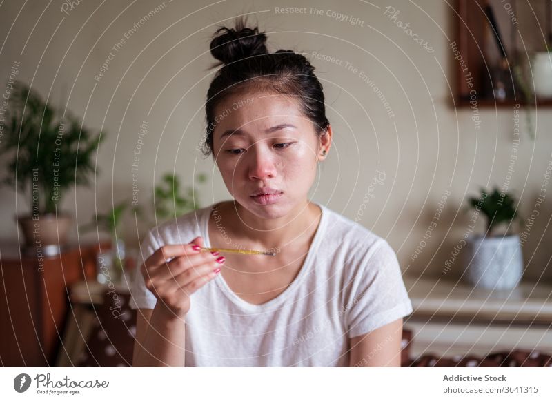 Kranke Asiatin misst Temperatur krank messen Frau Erkältung haben Grippe Thermometer heimwärts unwohl asiatisch ethnisch laufende Nase Einstecktuch Papier Bett