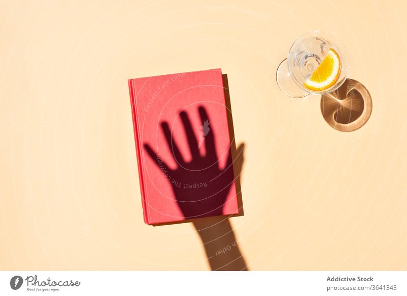 Hand der Erntehelferin und Notizbuch auf rosa Hintergrund Notebook Notizblock Person Tagebuch Atelier Glas Wasser Scheibe Schatten Erfrischung orange natürlich
