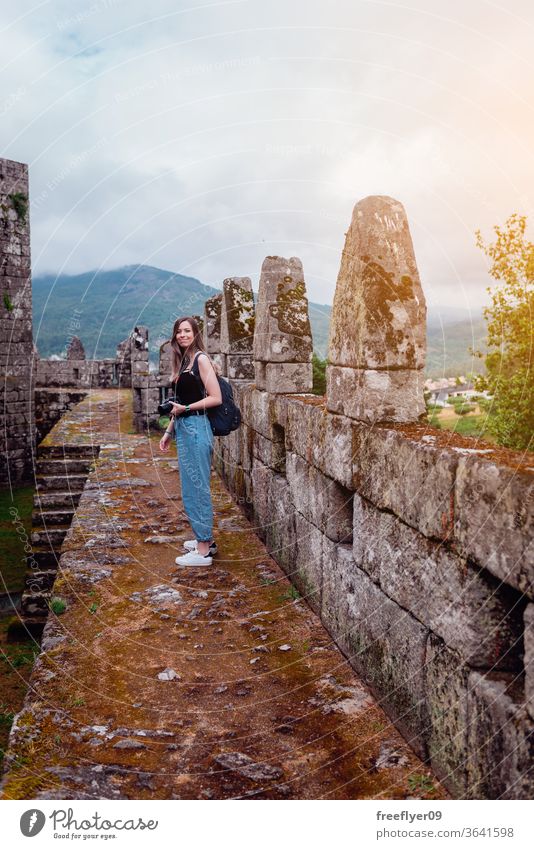 Weibliche Touristin mit Kamera Fotokamera Fotograf Frau Kaukasier blond Festungsmauern mittelalterlich Zinnen Burg oder Schloss Tourismus reisen Verlassen