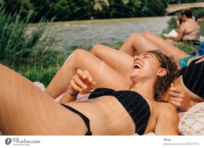 Junge Frau im Bikini genießt die Sonne und lacht mit ihren Freundinnen. Sommer und Lebensfreude.. Sonnenbaden Spaß lachen Freude Fröhlichkeit Spaß haben sonnen