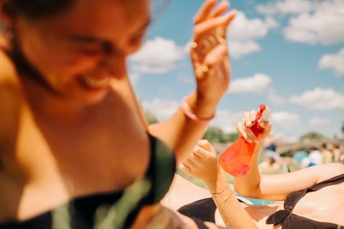 Zwei junge Frauen beim Baden, die Spaß haben und sich mit Wasser aus einer Sprühflasche bespritzen. Sommer und Lebensfreude. abkühlen Mädchen See Schwimmbad