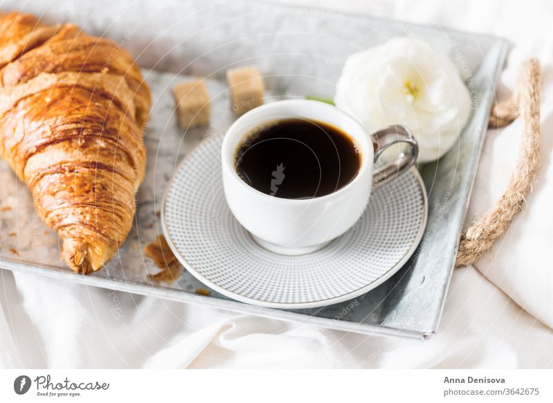 Frisches Croissant, Tasse Kaffee und Hahnenfußblüten. Frühstück im Bett Morgen Romantik Gebäck weiß Tisch Ranunculus Blumen trinken Tablett Espresso süß