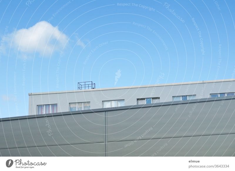 Blick über ein graues Zweckgebäude hinweg auf ein Bürogebäude mit Fenstern in Teilansicht vor blauem Himmel mit einer einzelnen Wolke Lagerhalle Dekowolke