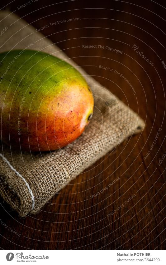 Mango auf Sackleinen Mangofrucht Farbfoto Holztisch Licht Frucht Südfrüchte juce jucy saftige Früchte Lebensmittel Gesunde Ernährung frisch
