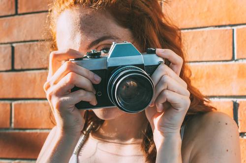 junge Frau hält eine analoge Kamera und schaut durch den Sucher veraltet Antiquität Antike Fotokamera klassisch Klassik klicken abschließen elektronisch Gerät