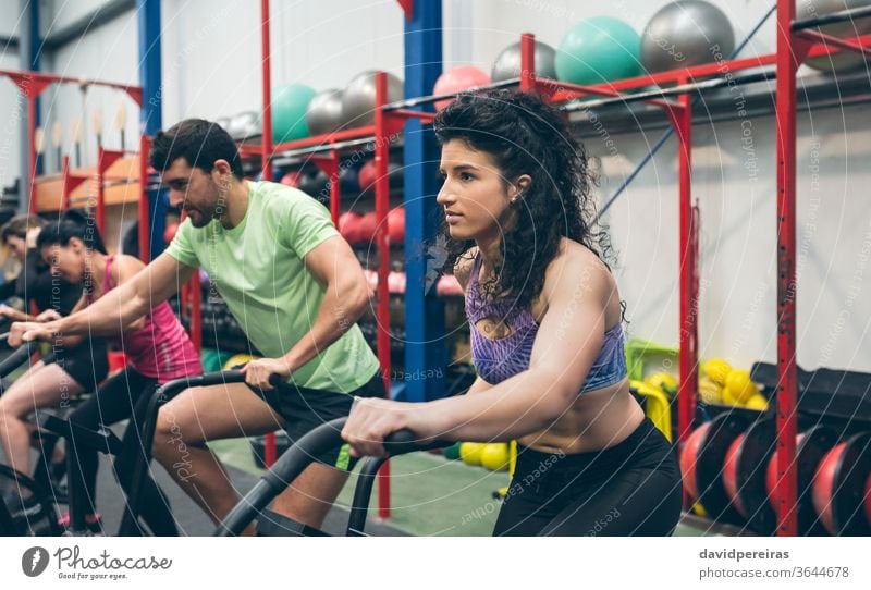 Athleten, die Indoor Airbike fahren Luftrad Frau Training Menschengruppe durchkreuzen passen Fitnessstudio Cross-Training Fahrrad Ausdauer Kraft Person jung