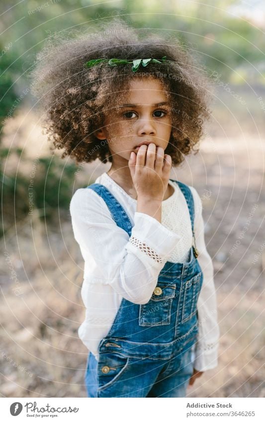 Ernstes kleines Mulattenmädchen auf verschwommenem Naturhintergrund Mädchen schwarz Kind ernst Porträt Windstille bezaubernd Sommer Stil Outfit emotionslos