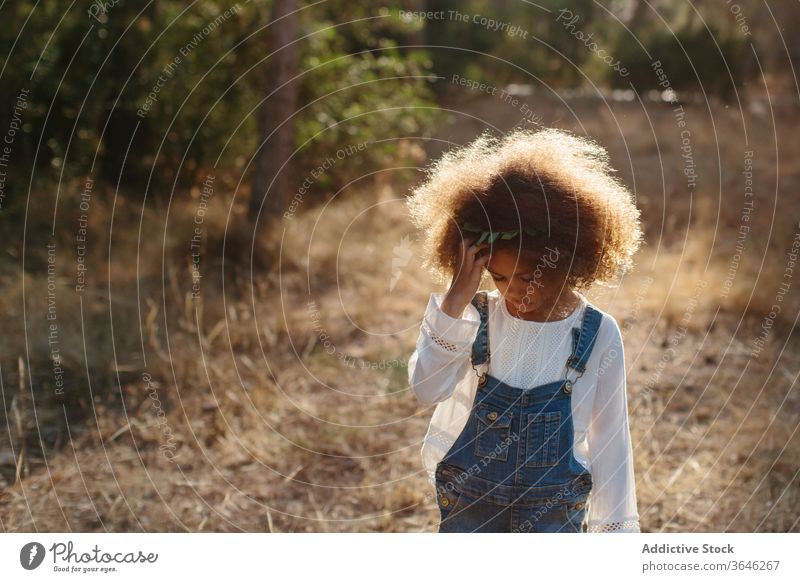 Ernstes kleines Mulattenmädchen auf verschwommenem Naturhintergrund Mädchen schwarz Kind Porträt Windstille bezaubernd Sommer Stil Outfit emotionslos