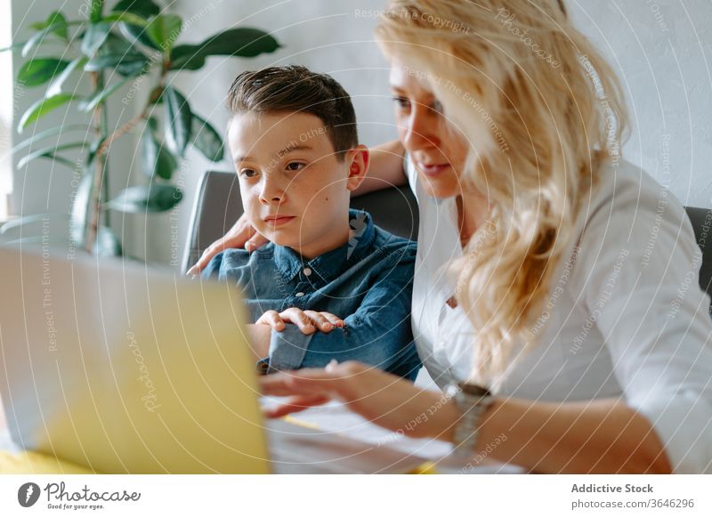 Positive Mutter mit Sohn am Laptop modern heimwärts Schulbildung Inhalt Browsen benutzend Wohnzimmer Eltern Tutorin lernen Lehrer Lektion Tisch Netbook