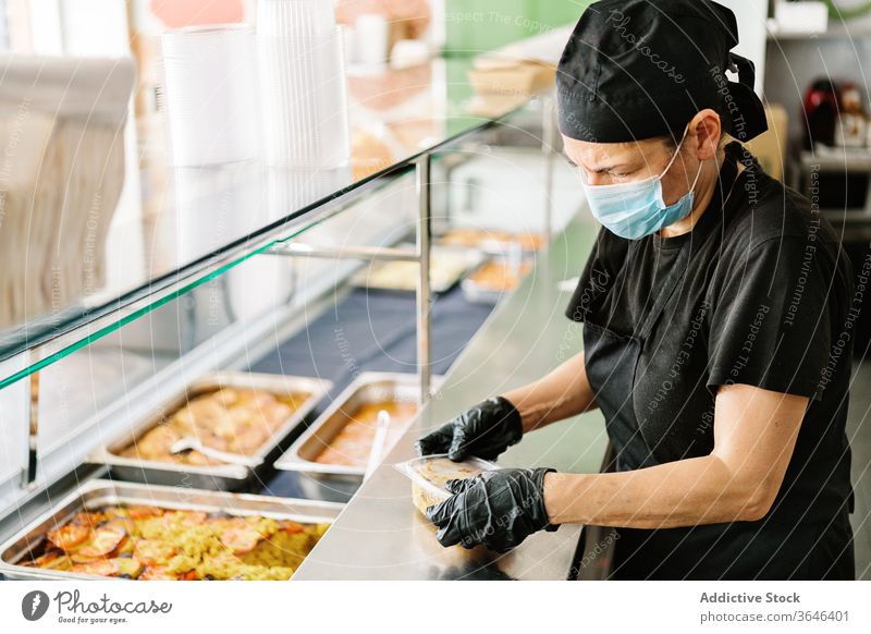 Cafe-Mitarbeiter packt Lebensmittel in Plastikbehälter zum Mitnehmen Kellnerin Atemschutzgerät Rudel Imbissbude Kunststoff Container Coronavirus geschmackvoll
