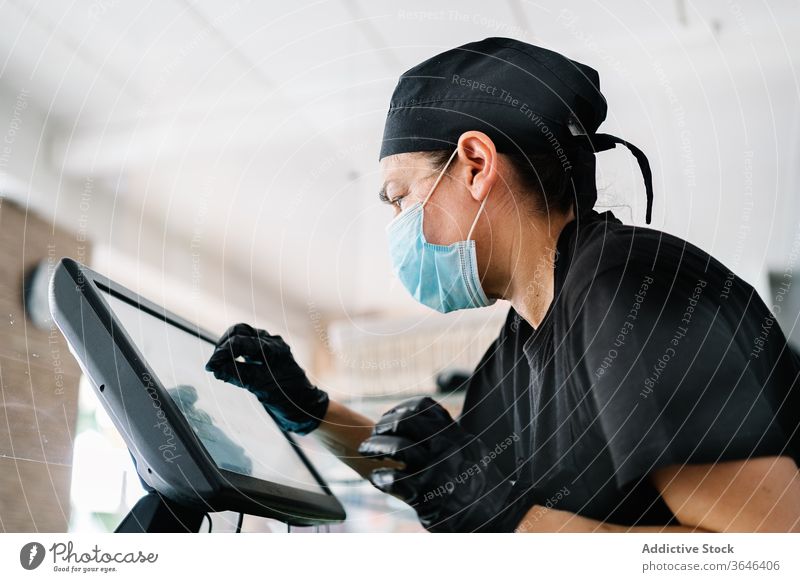 Fokussierte weibliche Kassiererin mit Gesichtsmaske, die mit der Kasse arbeitet Frau Arbeit Atemschutzgerät Abfertigungsschalter Café ernst Coronavirus