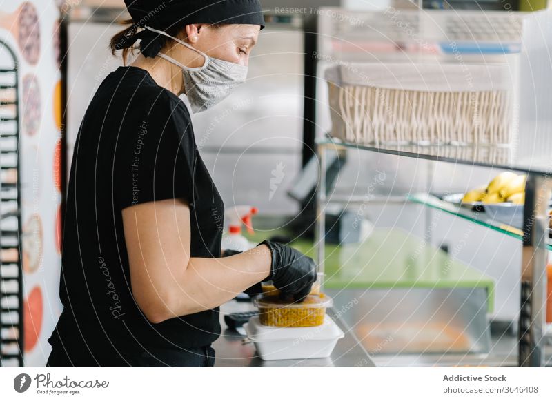 Cafe-Mitarbeiter packt Lebensmittel in Plastikbehälter zum Mitnehmen Kellnerin Atemschutzgerät Rudel Imbissbude Kunststoff Container Coronavirus geschmackvoll