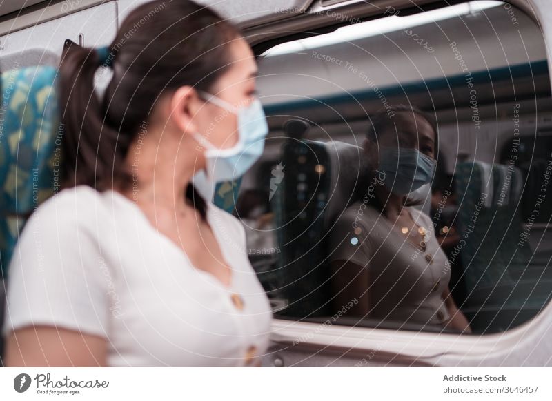 Ruhiger weiblicher Zugpassagier mit Atemschutzgerät schaut aus dem Fenster Frau Passagier Reflexion & Spiegelung Kabine nachts Ausflug Mundschutz Coronavirus