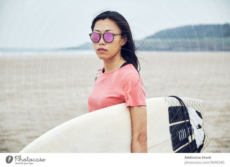 Zufriedene Surferin, die mit einem Surfbrett am Strand spazieren geht Frau Spaziergang sandig führen Inhalt MEER lässig Seeküste sorgenfrei Aktivität jung