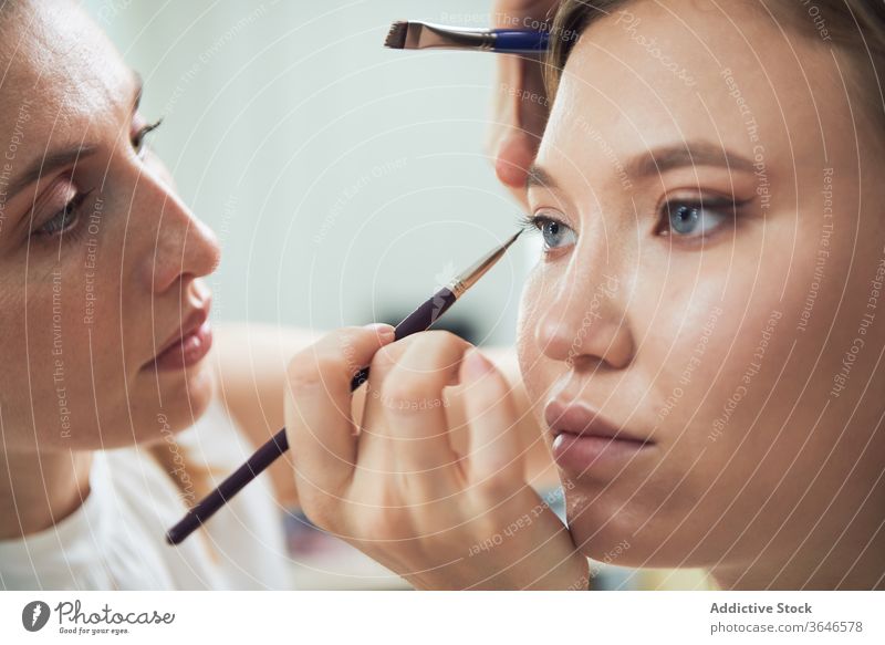 Stylistin beim Auftragen von Eyeliner auf das Modell visagiste Kajal Bürste Augenlid Make-up Atelier Fokus bewerben Konzentration Klient jung Beruf Kosmetik