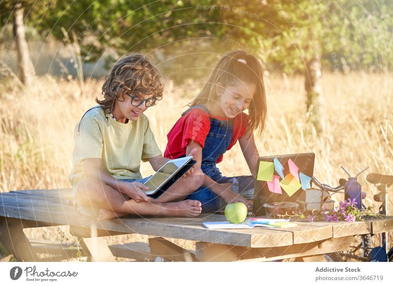 Zehnjähriger Junge und Mädchen machen ihre Hausaufgaben auf dem Feld an einem Tisch Freizeitkleidung Tag Pilze Europa laufen Shorts in voller Länge Bruder