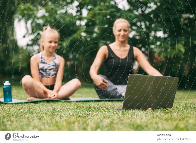 Mutter und Tochter üben während der Quarantäne-Selbstisolierung während einer Pandemie online im Freien in der Nähe ihres Zuhauses. Die Familie treibt gemeinsam von zu Hause aus online Sport. Gesunder Lebensstil