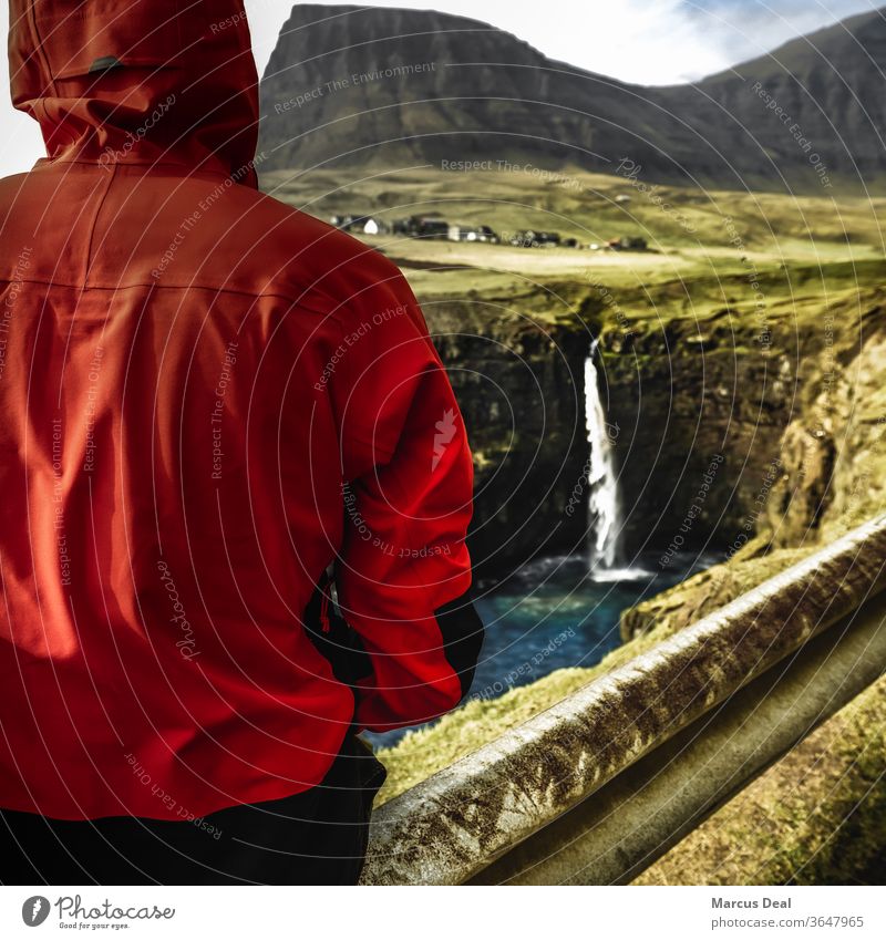 Einzelreisender mit Blick auf Wasserfall auf den Färöer-Inseln färöisch solo Alleinreisender eine Person rote Jacke ländlich Berge u. Gebirge Natur hübsch