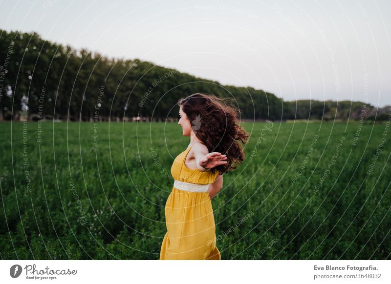 Porträt einer jungen schönen Frau, die ein gelbes Kleid trägt und in einem grünen Feld läuft. Sommerzeit und Lebensstil 1 Schönheit sorgenfrei lässig Kaukasier