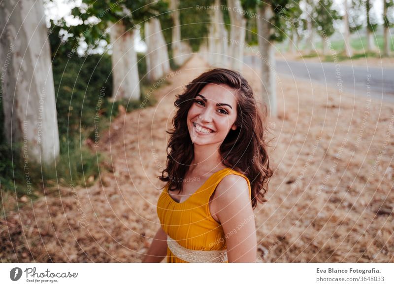 Porträt einer jungen schönen Frau in einem gelben Kleid, die in einem Pfad von Bäumen steht. Sommerzeit und Lebensstil Abenteuer Rücken Schönheit hell brünett