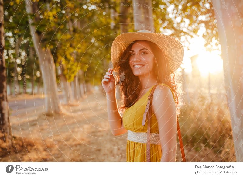 Porträt einer jungen schönen Frau in einem gelben Kleid, die an einem Pfad mit Bäumen entlang geht. Sommerzeit und Lebensstil Abenteuer Rücken Schönheit hell