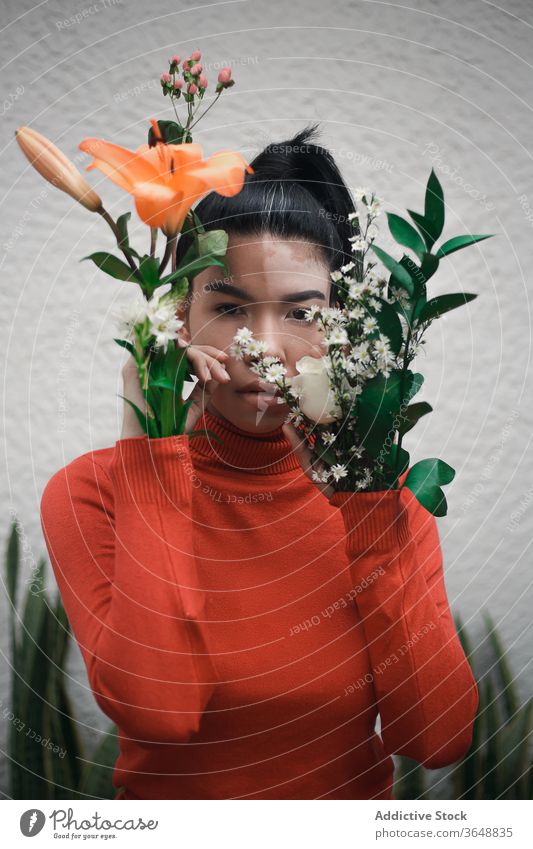Ethnische Frau mit Vitiligo-Haut hält Blumen zu Hause Harmonie Schönheit emotionslos natürlich Akzeptanz Blumenstrauß sanft heimwärts feminin Blatt Roséwein