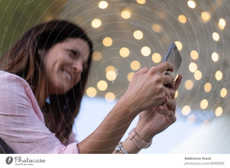 Lächelnde Frau mit Smartphone im Freien fotografieren Inhalt leuchten benutzend Foto Girlande Gedächtnis Moment Fotokamera Mobile Apparatur Fotografie