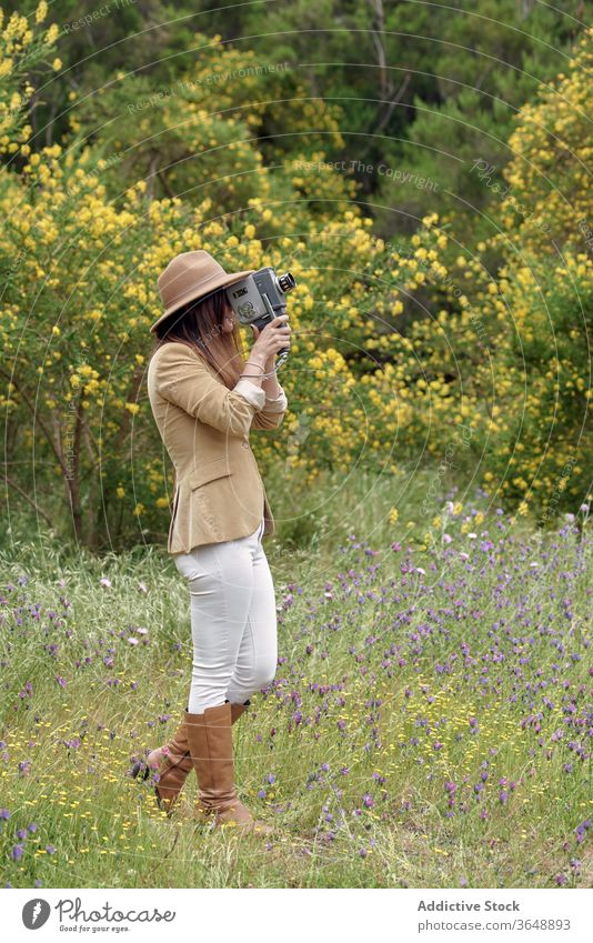 Fotograf, der mit einer alten Videokamera im Garten Videoaufnahmen macht Aufzeichnen Fotokamera Augen geschlossen Blütezeit Blume Baum Park Ast fokussiert
