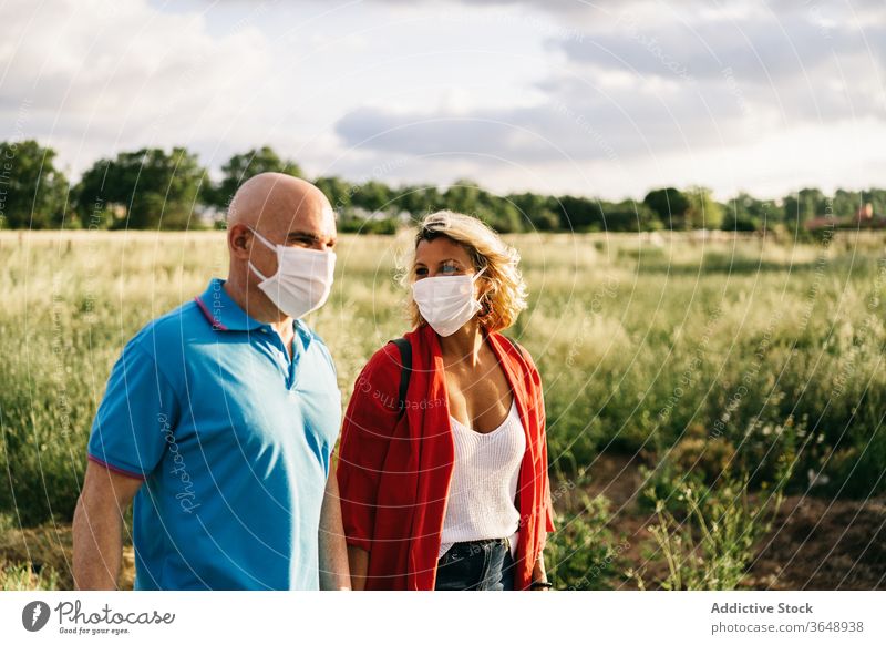 Paar mit Atemschutzmasken zu Fuß auf dem Land Spaziergang Atemschutzgerät lustig Coronavirus lässig Landschaft Mundschutz behüten Partnerschaft niedlich Bund 19