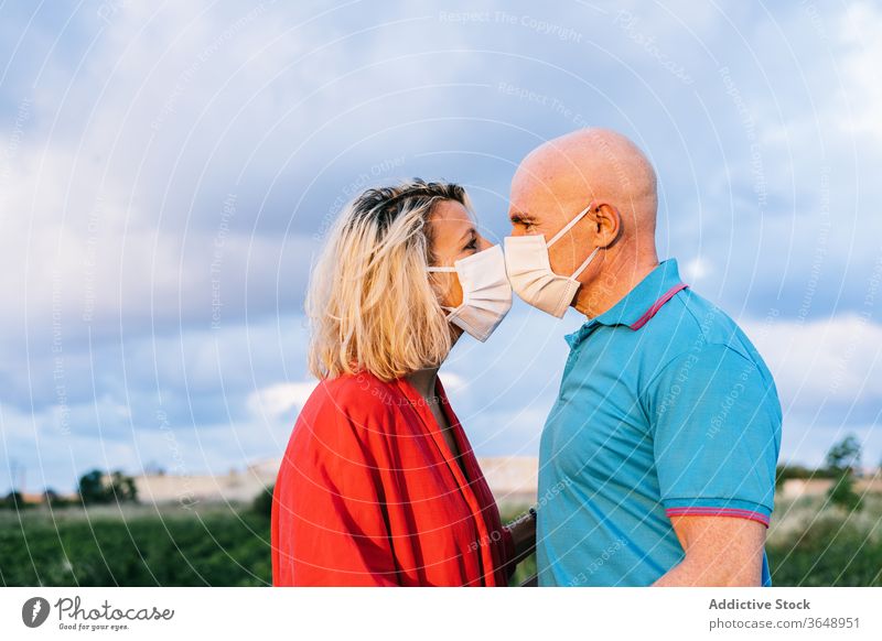 Romantisches Paar küsst sich durch Gesichtsmasken auf dem Land Mundschutz Kuss Landschaft Sommer romantisch Inhalt Bund 19 Partnerschaft Liebe Abend Zuneigung
